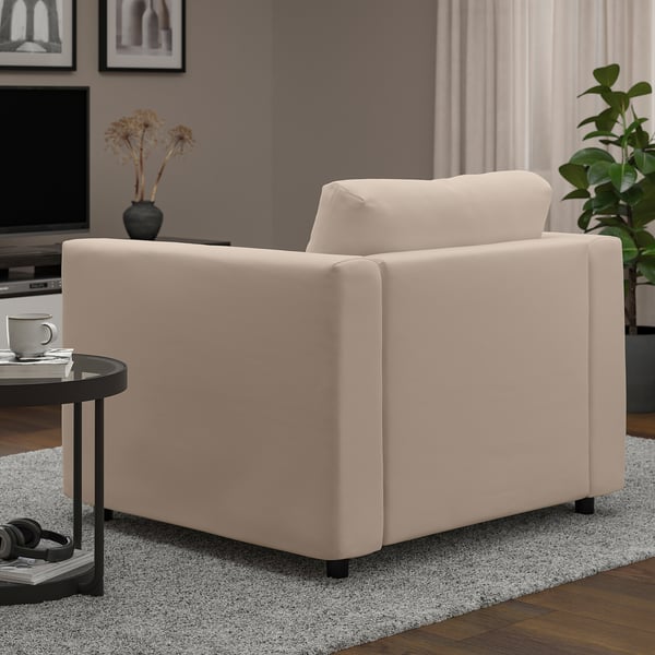 A beige VIMLE armchair in a living room, showcasing its soft, comfortable fabric and sturdy design with wooden floors and a rug beneath it.
