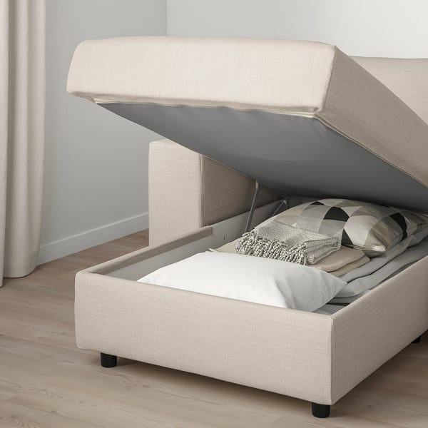 Sofa with open storage compartment, pillows, and cosy blanket inside.