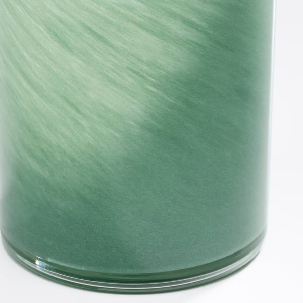 Close-up of handcrafted green glass candle holder, showcasing intricate, glowing patterns.