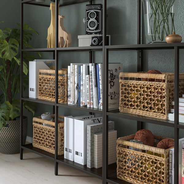 Black metal shelves with glass, displaying books, decorative baskets, and giraffe sculpture.