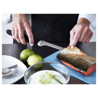 Person slices roasted fish with VÖRDA knife on blue cutting board, limes and sour cream nearby. Fish is golden, knife has smooth blade for filleting.