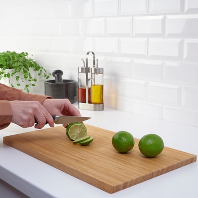 Person cutting limes on wooden board. Blade sharp, hand fits grip.