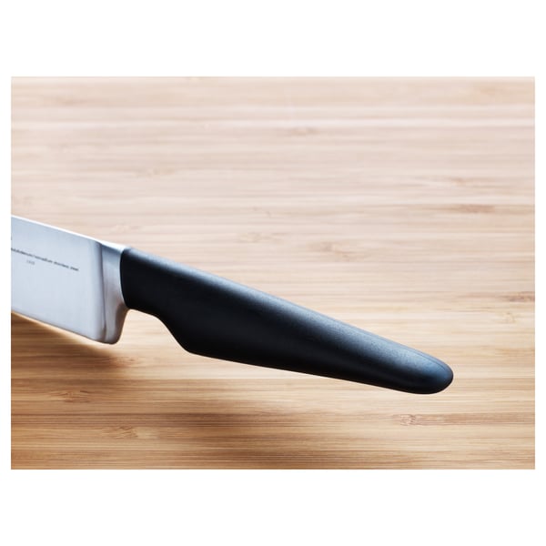 Knife on wood. Sharp stainless blade and ergonomic black handle. Professional kitchen tool.