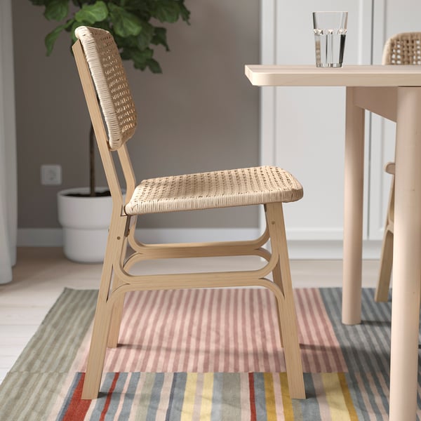 Chair with woven seat and back, placed on striped rug near dining table.