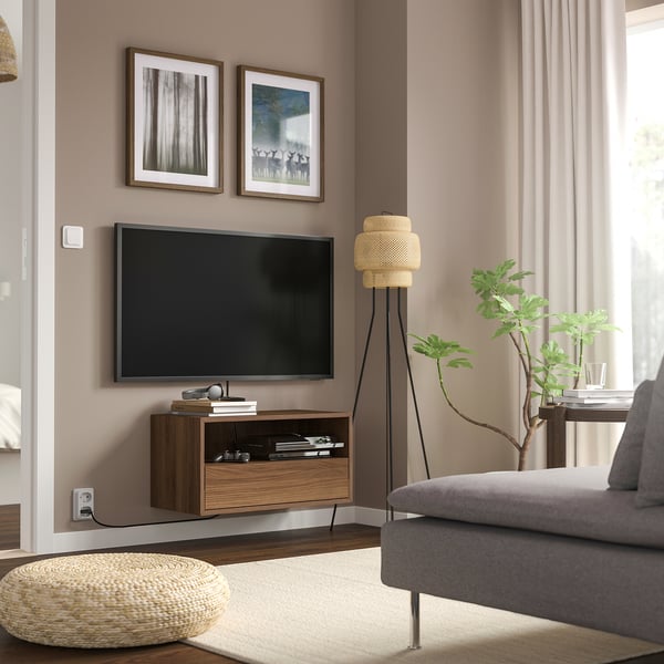 Moderni svetainė su televizoriumi media bloke, pilka sofa, augalas.