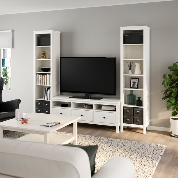 Moderni svetainė su HEMNES televizoriumi ir knygų spintomis, pilkomis sienomis, smėlio spalvos kilimu.