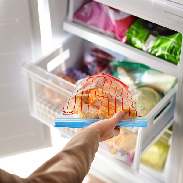 Asmenys, rankose laikantys daugkartinį, nepralaidų ir hermetišką maisto laikymo maišelį su ISTAD iš šaldiklio.