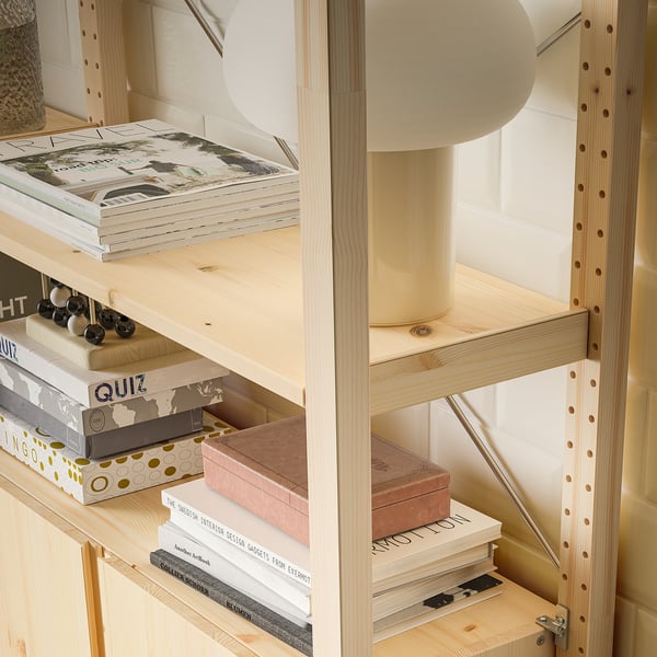 Medinė knygų lentyna su reguliuojamomis lentynomis, kurioje eksponuojami įvairūs daiktai, įskaitant knygas, lempą ir žaidimų lentas.