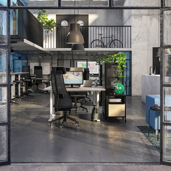 Modernus biuras su ergonomiškomis kėdėmis, dideliais monitoriais ir pramoniniu dekoru.