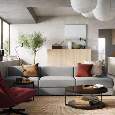 Moderni svetainė su pilka sofa, raudonais akcentais, spintele, kavos staliuku ir dideliu langu.