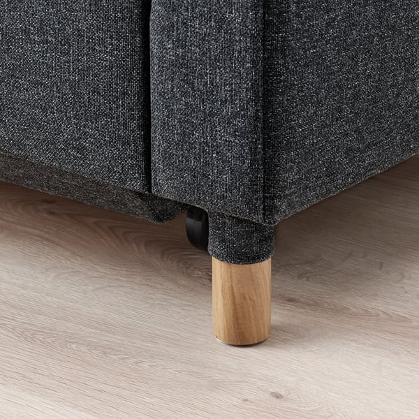 Moderni, minkšta sofa-lova su medinėmis kojomis ir grindimis stambiu planu. Kokybiška mediena, stilinga ir ilgaamžė.
