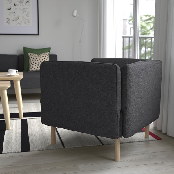 Moderni svetainė su tamsiai pilka LILLEHEM sofa, juodai baltu dryžuotu kilimu ir dideliu langu.