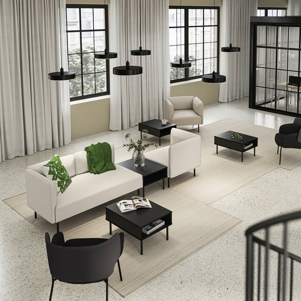 Moderni svetainė su kremine sofa, juodais stalais, dideliais langais.