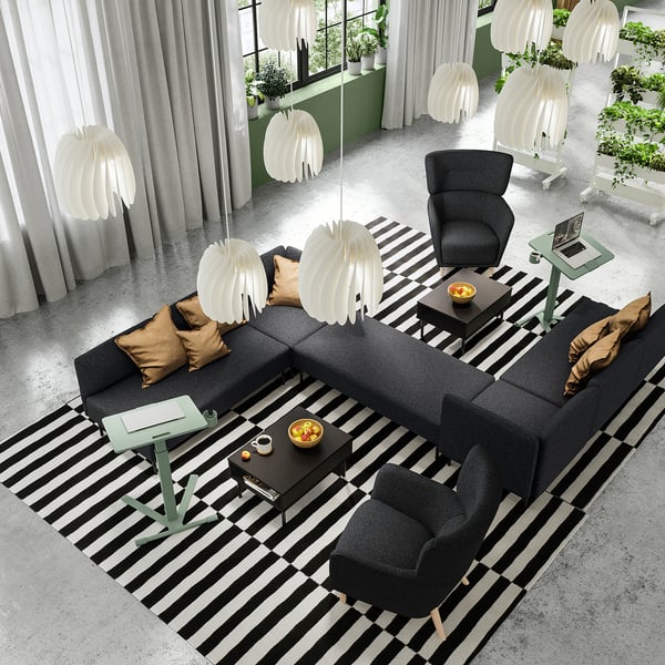 Modernus vestibiulis su juoda sofa, foteliais ir reguliuojamo aukščio nešiojamųjų kompiuterių stalais.