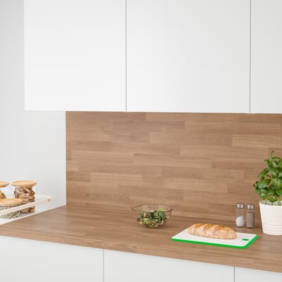 Modernus virtuvės prekystalis su mediniu backsplash. Duona, žalumynai, konteineriai ir augalai sėdi ant prekystalio.