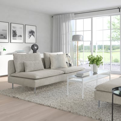 Sofa SÖDERHAMN, smėlio spalvos, žema ir jauki, idealiai tinkanti lounging. Padėtas centre su kilimu, vaizdingais langais.