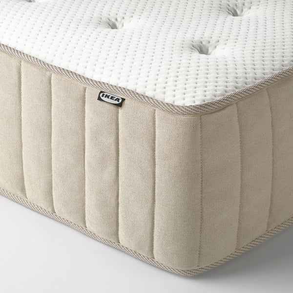 Tvirto kišeninio spyruoklinio čiužinio su natūraliomis medžiagomis kampas. Sustiprinti kraštai, matoma IKEA etiketė.