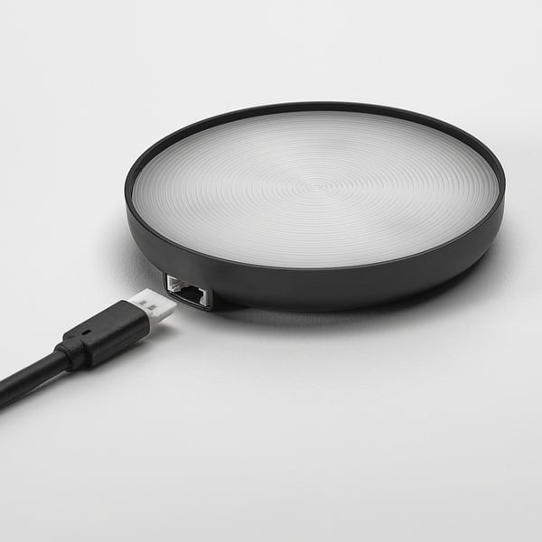 Круглое беспроводное зарядное устройство, лаконичный дизайн, черного цвета с тонкими концентрическими кругами, соединено usb-кабелем.