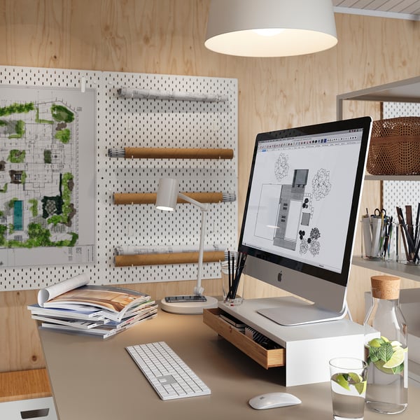 Домашний офисный стол с imac, клавиатурой, мышью, лампой и книгами. Пегборд с планами и иллюстрациями. Белый и деревянный декор.