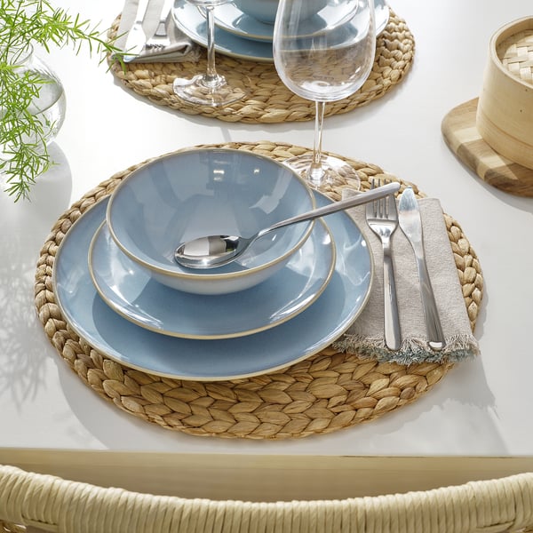 Сервировка стола с голубой посудой FÄRGKLAR, ткаными салфетками, столовым серебром и стеклом.
