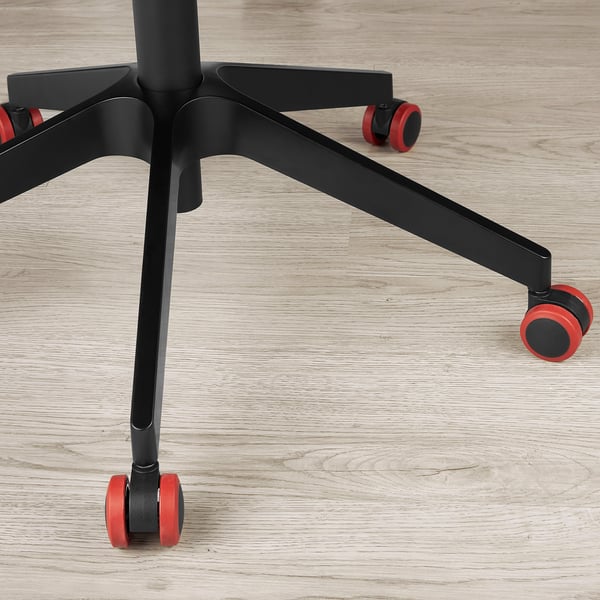 Черное основание офисного кресла с красными колесиками на деревянном полу. Прочная конструкция, ролики с плавным раскатыванием.