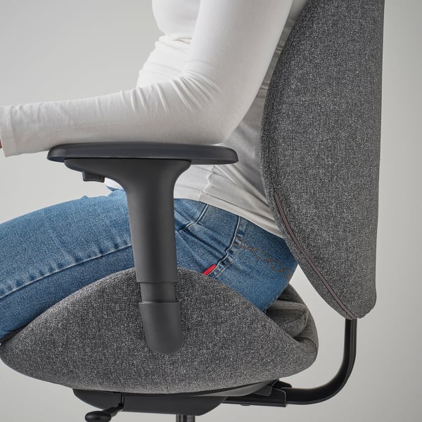 Человек сидит в сером офисном кресле HATTEFJÄLL, демонстрируя синхронизированный механизм наклона в действии.