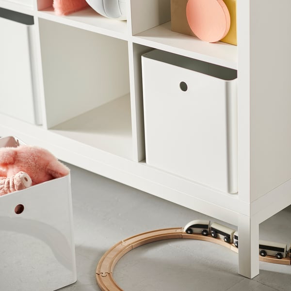 Белый стеллаж KALLAX с коробками и игрушечным поездом.