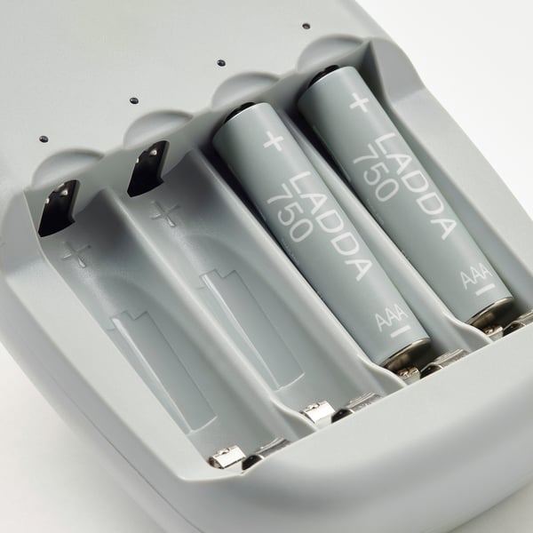 Четыре серые аккумуляторные батареи типа ААА с маркировкой LADDA 750 помещены в белый держатель с видимым логотипом бренда.
