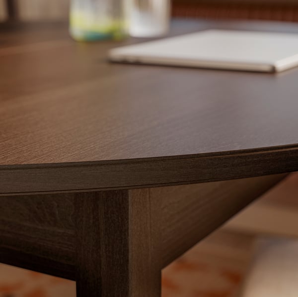 Крупный план хорошо изготовленного деревянного стола с гладкой темной отделкой и видимой текстурой дерева, демонстрирующий его крепкие ножки со скошенными фаски.