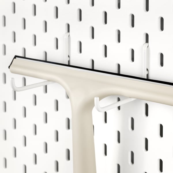 Белый крючок SKÅDIS, прикрепленный к пегборду; Надежно удерживает предметы.