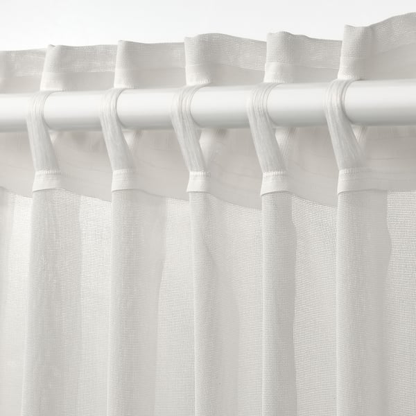 White sheer curtain with grommet rod pocket, allowing light and shapes to philtre through, ideal for wide windows.
