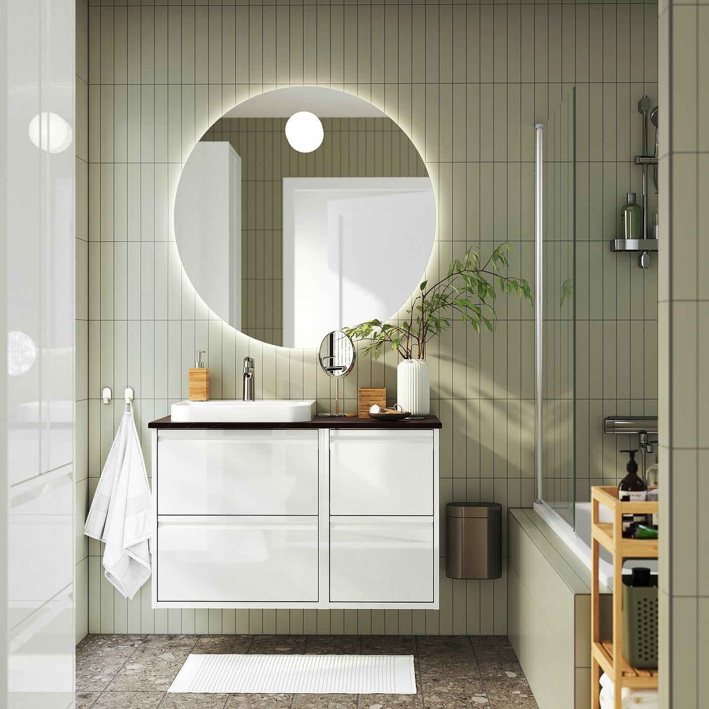 Modern bathroom with ÄNGSJÖN vanity, mirror, shower, towel, plant, and storage rack.