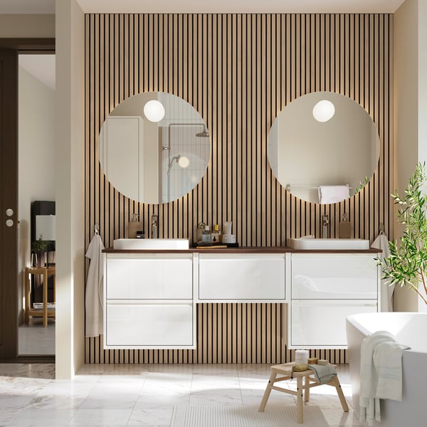 Modern bathroom with white ÄNGSJÖN vanity, dual sinks, mirrors, and bold wallpaper.