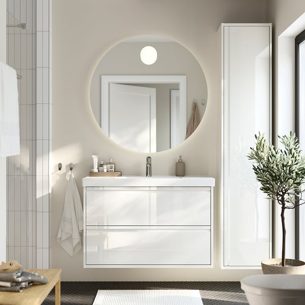 Modern white bathroom vanity with 2 drawers, ceramic basin, and round mirror for minimalist theme.