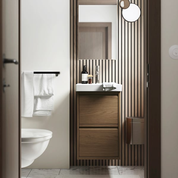Modern bathroom with dark wood ÄNGSJÖN cabinet, handles, washbasin, and storage drawers.