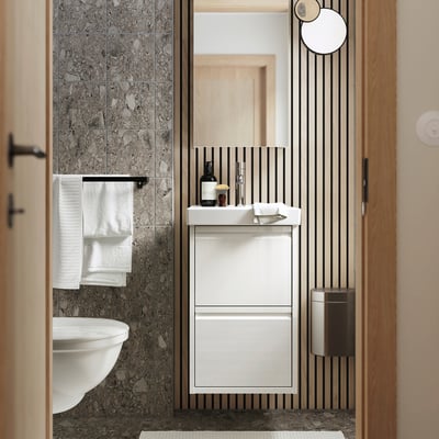 A modern bathroom with a white ÄNGSJÖN vanity unit featuring two drawers, minimalist design, and integrated handles.