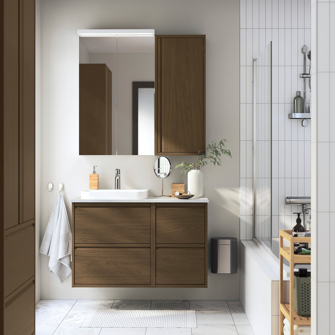 Modern bathroom with wooden vanilla cabinet, big mirror, white sink, towel, and plant. Cabinets and mirror take up little space.