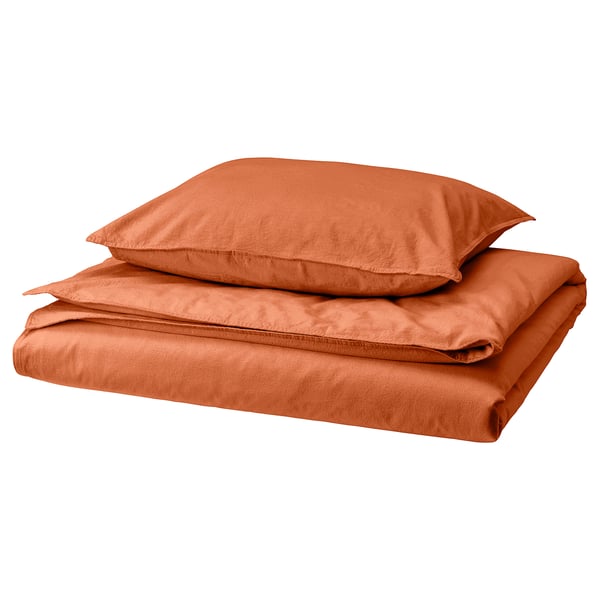 Folded burnt orange bedding set, featuring duvet cover and pillowcase in soft cotton, displayed neatly.