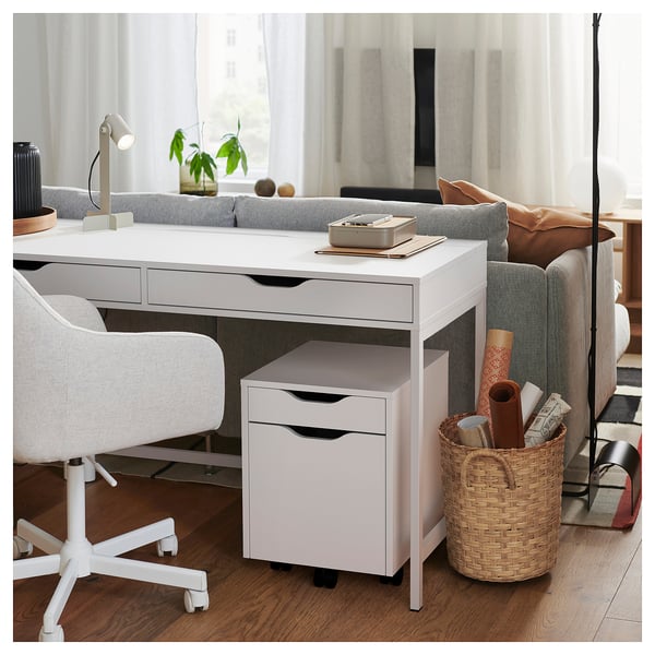 Home office setup with white ALEX desk and drawer unit, chair, lamp, and basket with supplies.
