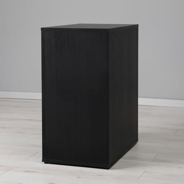 Black square storage cabinet with smooth finish, standing alone on a light wooden floor.