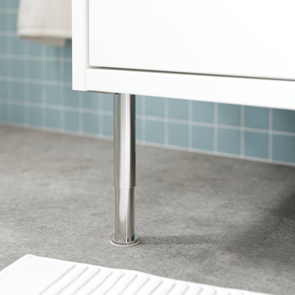 Metal leg stabilises white bathroom cabinet against blue tiled wall.