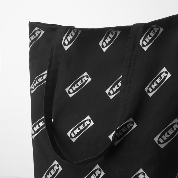 Black tote bag with repeated ikea logos, durable cotton material, sturdy handles, suitable for daily use.