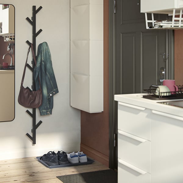 Hallway with black shoe mat, coat rack, denim jacket, maroon purse.