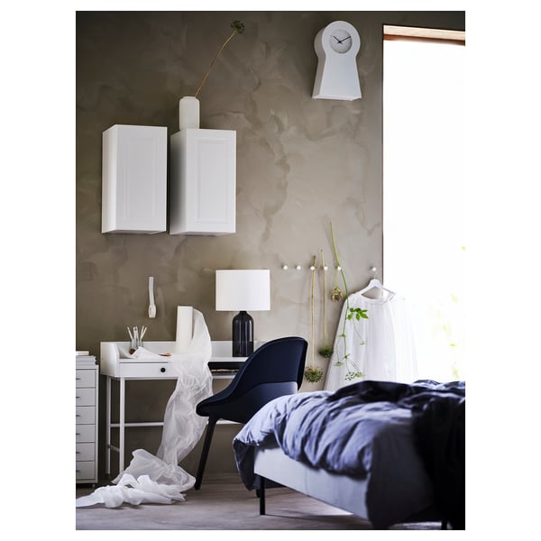 Modern bedroom with monochromatic decor, featuring a desk, floating cabinets, bed, and clock.