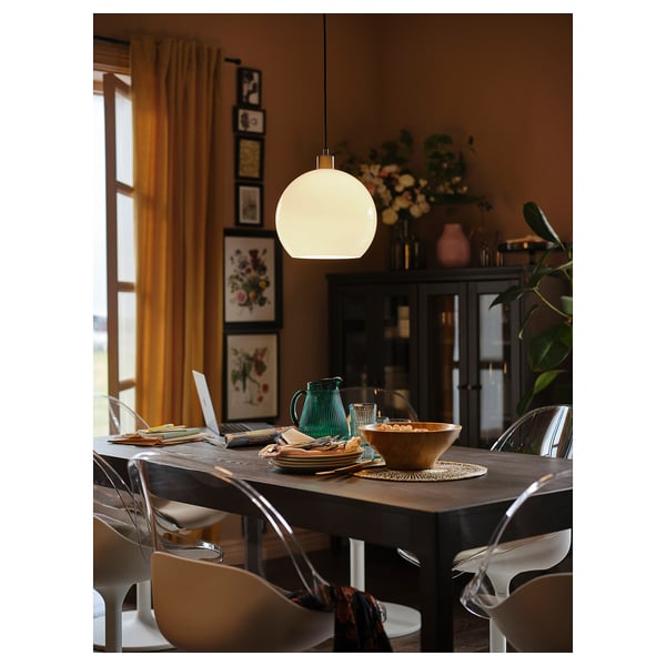 Modern dining area with wooden table, white swivel chairs, hanging light, plants, and decor.