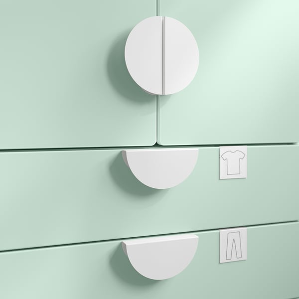 Three pastel pink, circular storage handles attached to light green surfaces.