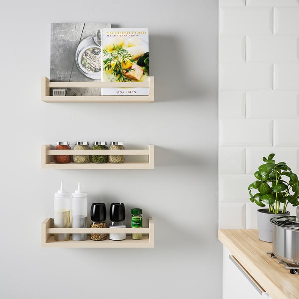 Wooden shelves hold cookbooks, spices, condiments, and a plant.
