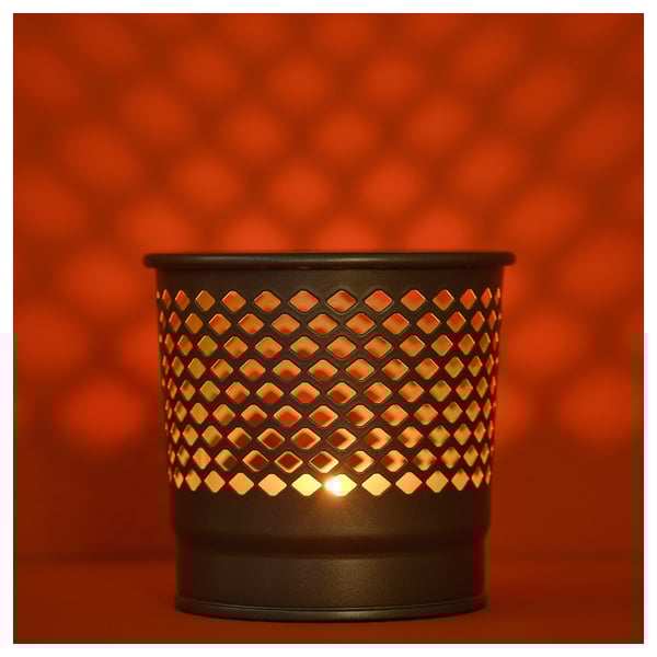 Black candle holder with diamond cutouts. Light shines warmly through metal.