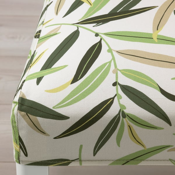Close-up of a BERGMUND dining chair with green leaf pattern; vibrant, removable cover.