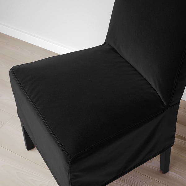 Black upholstered chair with plush fabric and wood legs.